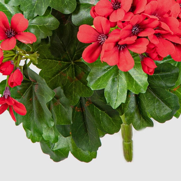 Künstliche Geranie mit roten Blüten und grünen Blättern in Nahaufnahme.