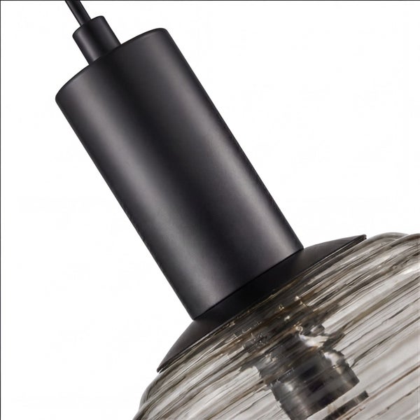 Nahaufnahme einer Pendelleuchte mit geriffeltem Glasschirm und zylindrischer Halterung aus Metall.