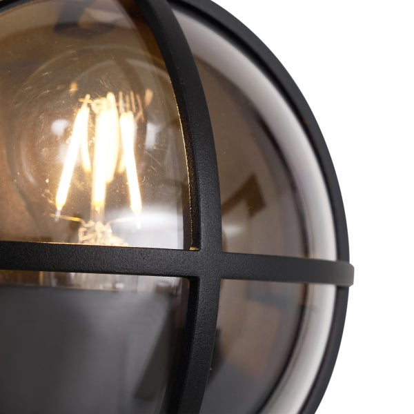 Runde Außenwandleuchte mit schwarzem Gittergehäuse und leuchtendem LED-Filament-Leuchtmittel.