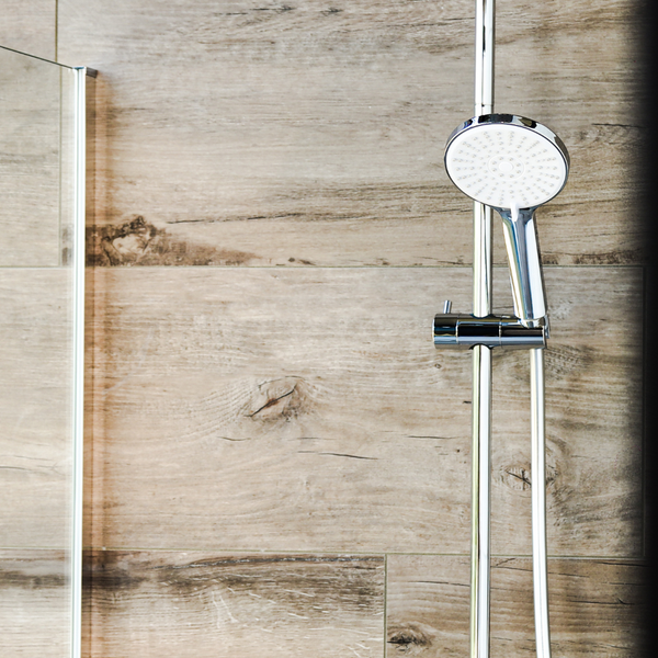 Duschstangenset mit Handbrause vor einer Wand mit Holzoptik Fliesen in einem modernen Badezimmer.