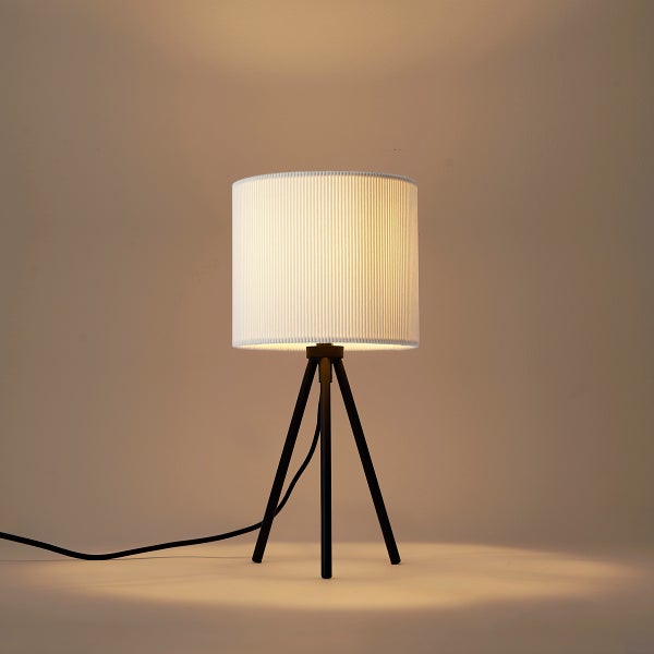 Dreibein-Tischleuchte mit weißem, geripptem Zylinderschirm und schwarzem Gestell.