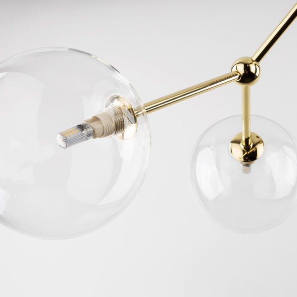 Detailaufnahme einer Lampe mit transparenten Glaskugeln und goldenem Gestell