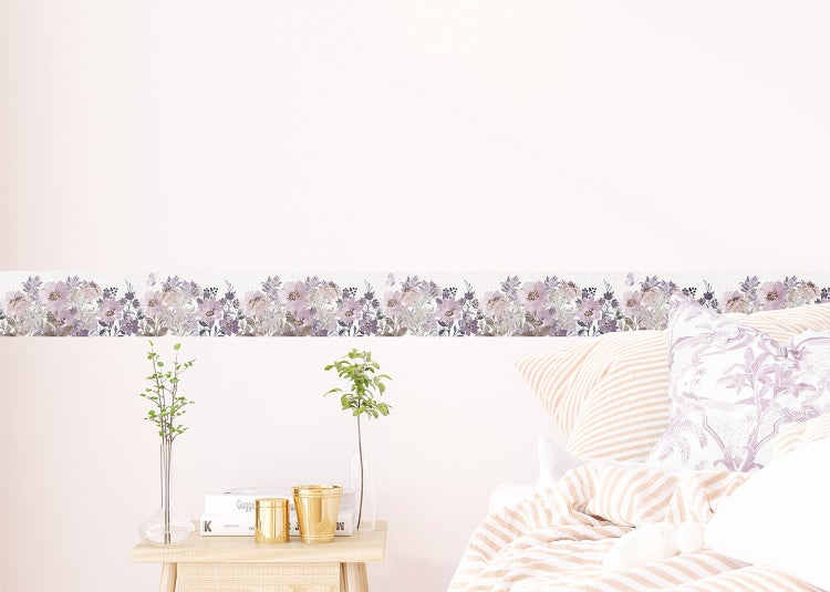 Tapetenbordüre mit floralem Muster aus lila und beigen Blumen an einer Wand in einem hellen, ordentlichen Schlafzimmer.