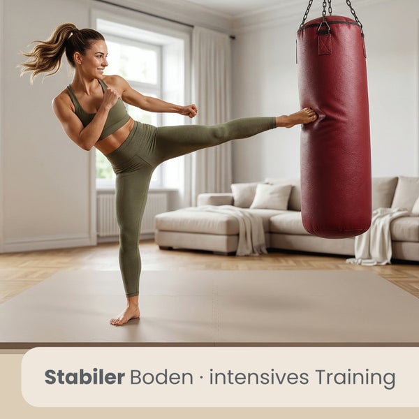 Frau trainiert intensiv mit Boxsack auf einer stabilen Bodenmatte in einem hellen Wohnzimmer.