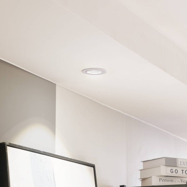 Runder LED-Einbaustrahler in einer Decke, eingeschaltet in einem hellen, modern eingerichteten Raum.
