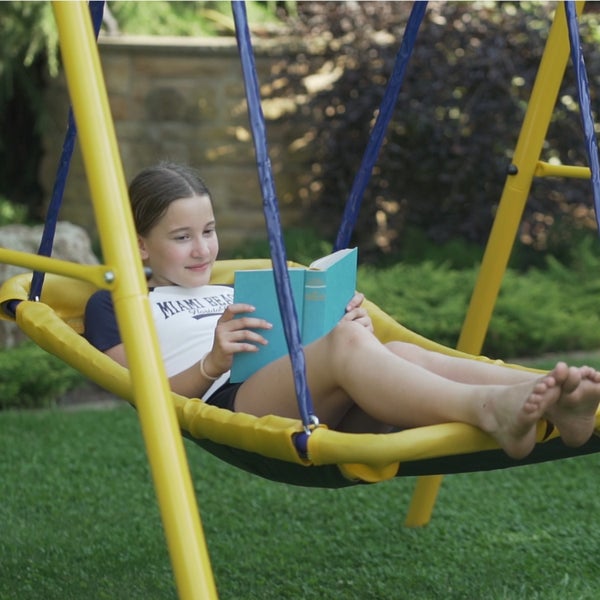 Mädchen liest Buch in Hängeschaukel im Garten