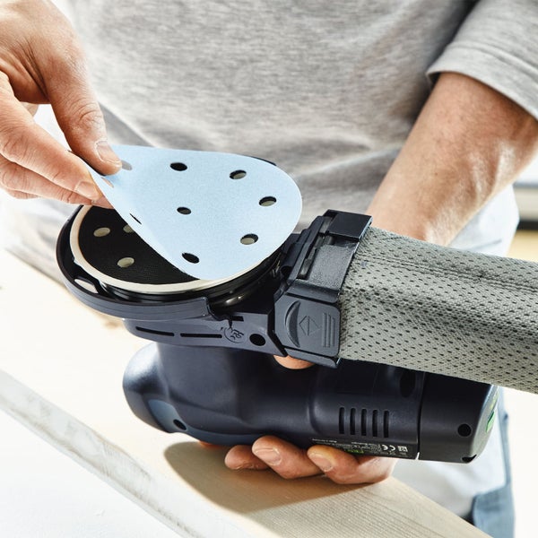 Person befestigt Schleifpapier auf einem Exzenterschleifer.