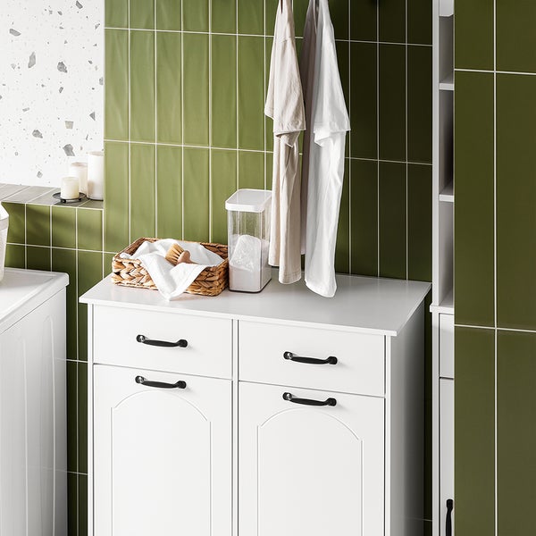 Wäscheraum mit weißen Schränken, Wäschekorb und Waschmittelbehälter.