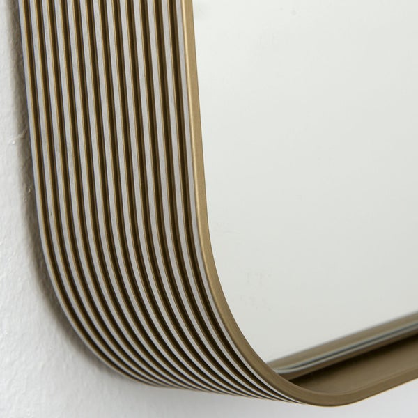 Detailansicht eines Wandspiegels mit abgerundeter Ecke und einem gerippten Rahmen.