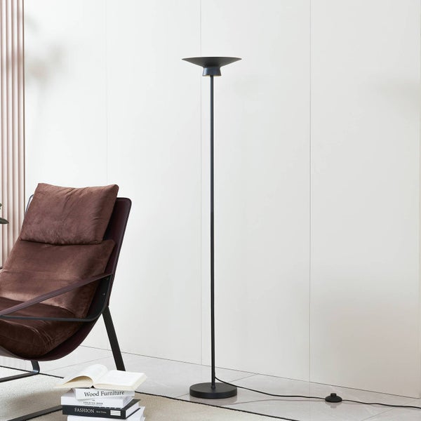 Moderne schwarze Stehleuchte mit minimalistischem Design und schalenförmigem Schirm, in einem Raum neben einem braunen Samtsessel und Büchern.