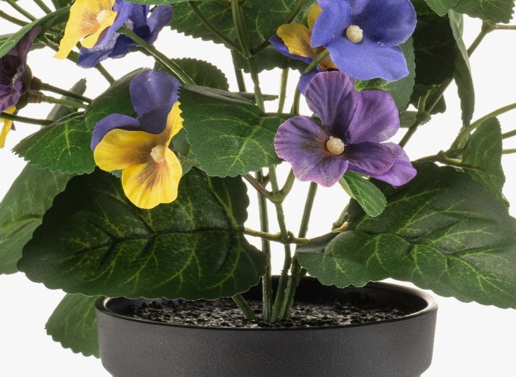 Künstliche Stiefmütterchen im schwarzen Topf mit violetten und gelben Blüten sowie grünen Blättern.