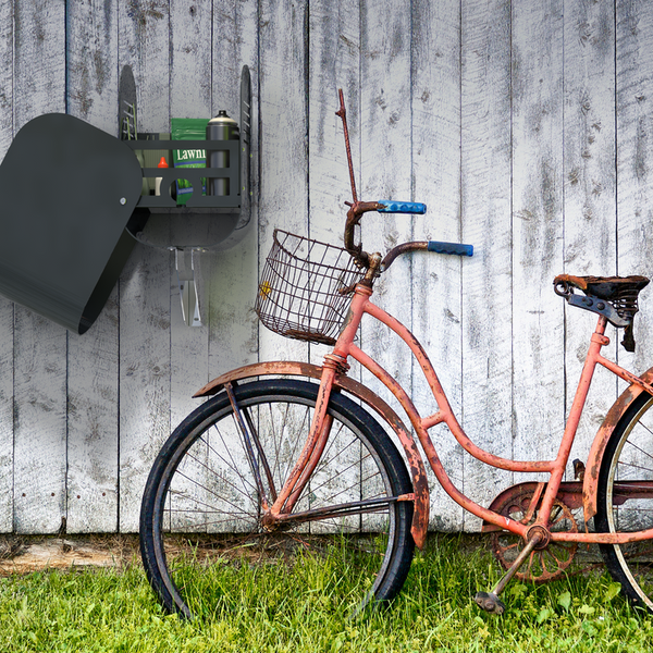 Eine Gartenszene mit einem Werkzeugschrank und einem Fahrrad vor einer Holzwand.
