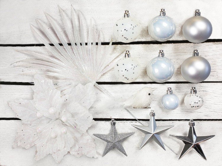 Weihnachtsbaumschmuck Set in Weiss und Silber mit Weihnachtskugeln, Sternen, einer Kunstblume und einem Dekovogel auf Holzuntergrund.