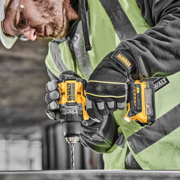 Handwerker bohrt mit einem DeWalt Akku-Bohrschrauber und trägt Arbeitshandschuhe sowie Sicherheitsausrüstung.