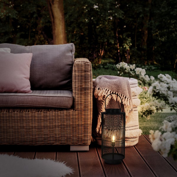 Szene mit Kräutern in Tontöpfen, Gemüse und Küchenutensilien auf einem Küchentisch.