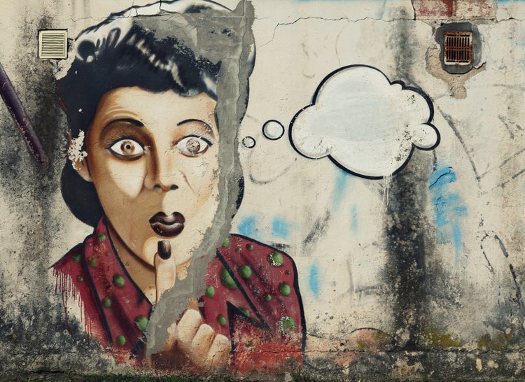 Wandbild mit Graffiti einer überraschten Frau in rotem Oberteil mit Finger vor dem Mund und einer Gedankenblase auf einer alten Wand.