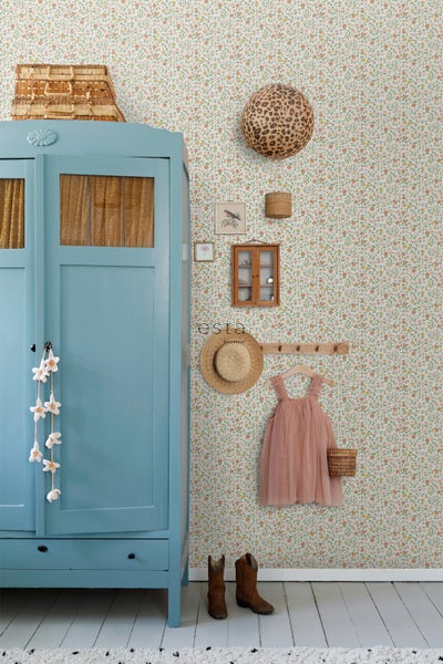 Dekoratives Kinderzimmer mit floraler Tapete, blauem Schrank und Accessoires.