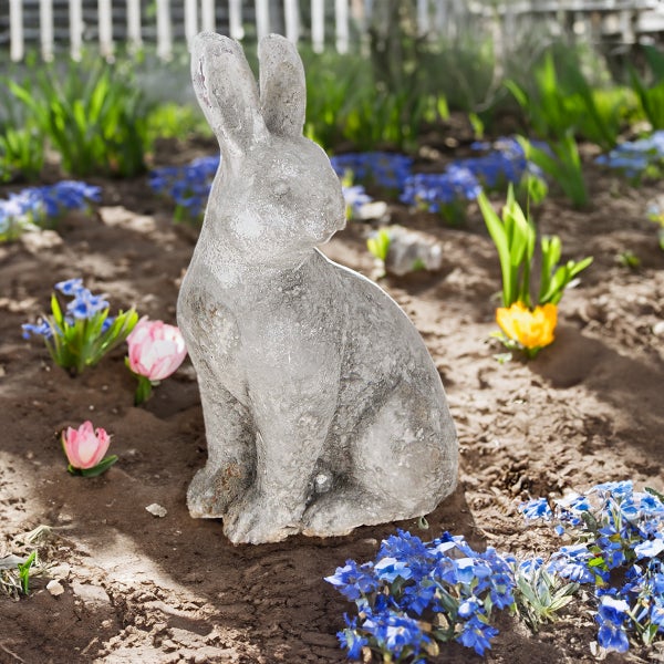Dekorative Hasenfigur im Gartenbeet