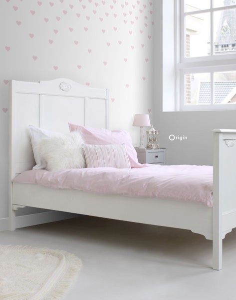 Helles Schlafzimmer mit weißem Bett, Bettwäsche und Herzdekoration an der Wand