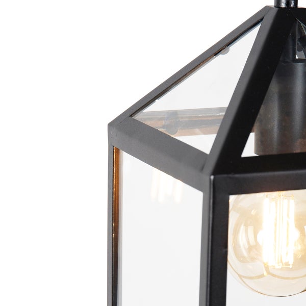 Detailaufnahme einer schwarzen Außenleuchte in Laternenform mit Glaseinsätzen und leuchtendem Filament-Leuchtmittel.