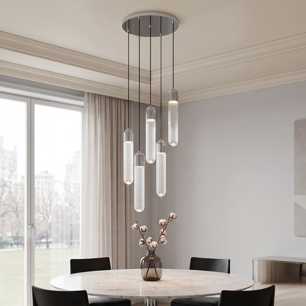 Moderne Hängeleuchte mit fünf geriffelten Glaszylindern über einem runden Esstisch in einem hellen, elegant eingerichteten Esszimmer.
