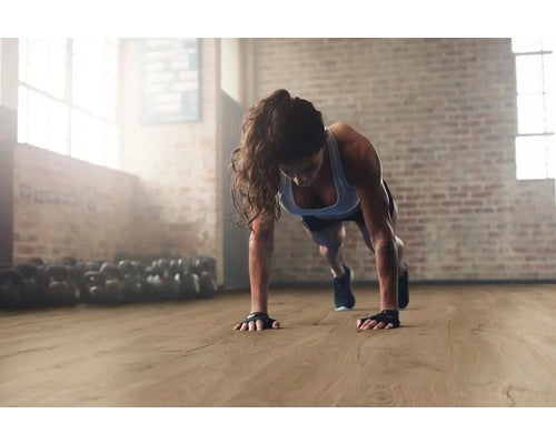 Frau macht Liegestütze auf Holzboden in einem Fitnessstudio