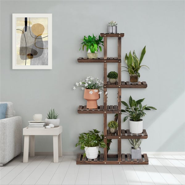 Mehrstöckiges Pflanzenregal aus Holz mit verschiedenen Zimmerpflanzen in einem Wohnzimmer.