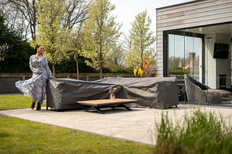 Gartenszene mit abgedeckter Sitzgruppe, einem Couchtisch und einer Frau in einem Kleid