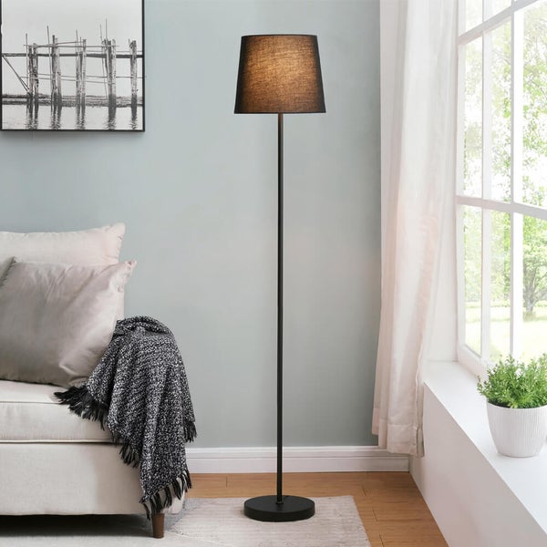 Stehlampe mit Schirm und Metallfuß in einem hellen, freundlichen Wohnzimmer.