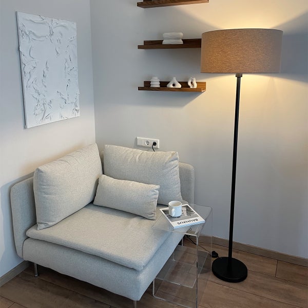 Wohnzimmer-Szene mit Sessel, Stehlampe und Wanddekoration für eine gemütliche Atmosphäre