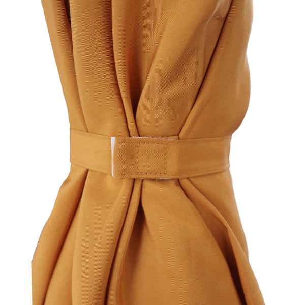 Nahaufnahme eines senfgelben Stoffvorhangs mit Raffhalter und Klettverschluss.