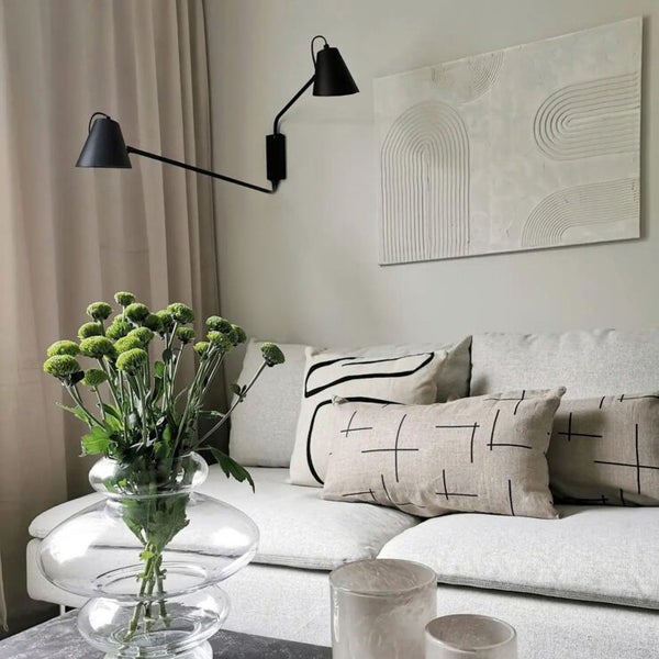 Wohnzimmer mit Sofa, Kissen, Wandleuchten und Dekoration für ein helles, organisiertes Ambiente