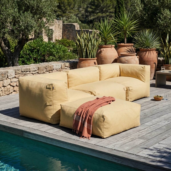 Outdoor-Sitzsack-Eckmodul aus gelbem Textil auf einer Holzterrasse am Pool.