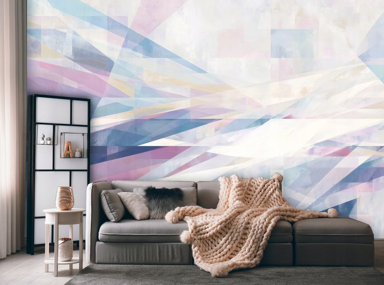 Wohnzimmer mit Sofa, Kissen, Überwurf, Beistelltisch und Wandregal vor einer Wandtapete mit geometrischen Formen