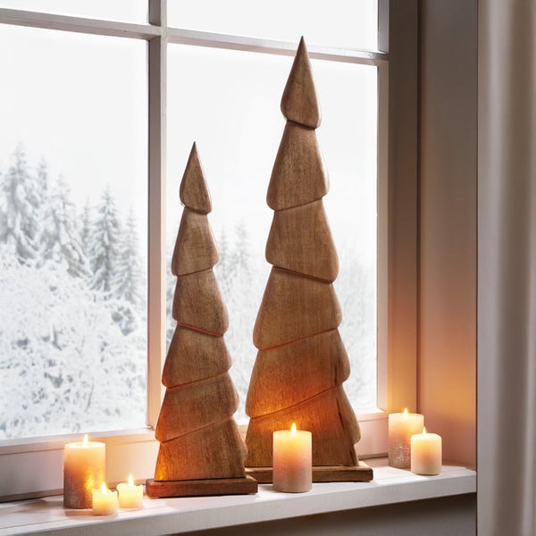 Dekorative Holzbäume und Kerzen auf einer Fensterbank