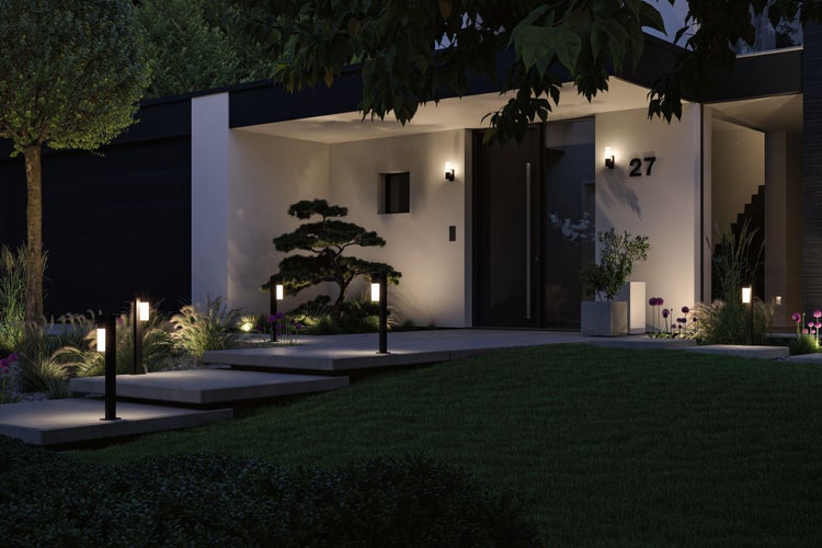 Moderner, beleuchteter Hauseingang mit Wegeleuchten an Betontreppen, Wandleuchten und gepflegter Gartenlandschaft bei Nacht.