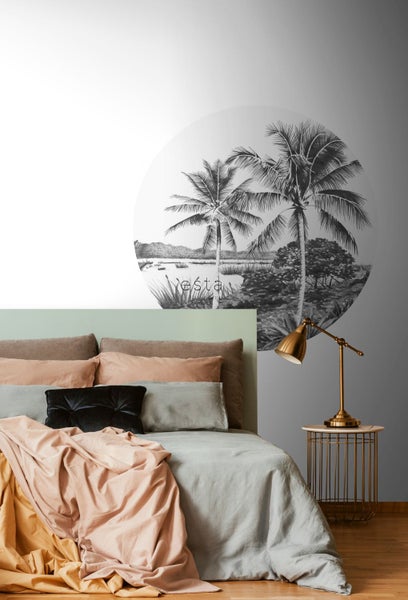 Schlafzimmer mit Bett, Nachttischlampe und Wandbild mit Palmenmotiv