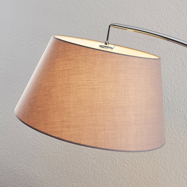 Stoff-Lampenschirm einer Bogenleuchte an einem gebogenen Metallarm, beleuchtet.