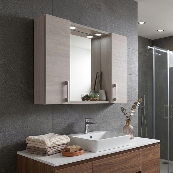 Moderner Spiegelschrank in heller Holzoptik mit integrierter LED-Beleuchtung über einem weißen Aufsatzwaschbecken in einem grauen Badezimmer.