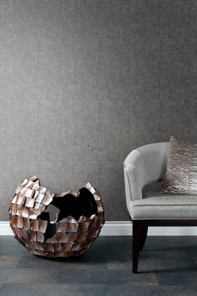 Dekorative Raumszene mit grauen Wand- und Bodenfliesen, einer zerbrochenen Kugel und einem Sessel