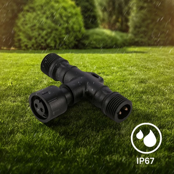 Schwarzer T-Verbinder aus Kunststoff für Gartenbeleuchtung auf einem Rasen im Regen, wasserdicht nach Schutzart IP67.