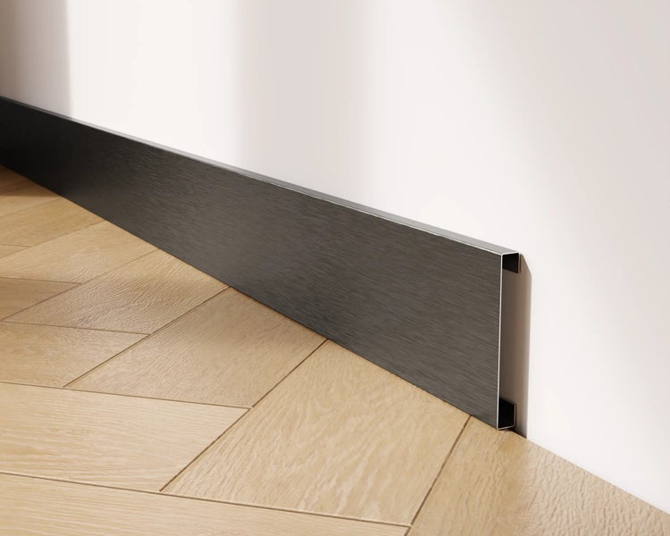 Sockelleiste aus Metall vor einer Wand und einem Holzboden