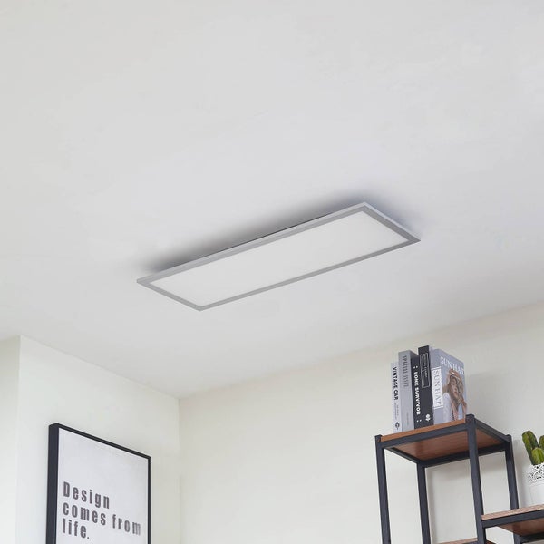 Flaches, rechteckiges LED-Panel an der Decke in einem hellen, modern eingerichteten Raum mit Regal und Wandbild.