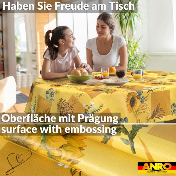 Frau und Kind am Tisch mit Sonnenblumen-Tischdecke und geprägter Oberfläche in hellem Esszimmer. Deutsche Manufaktur. ANRO Logo.