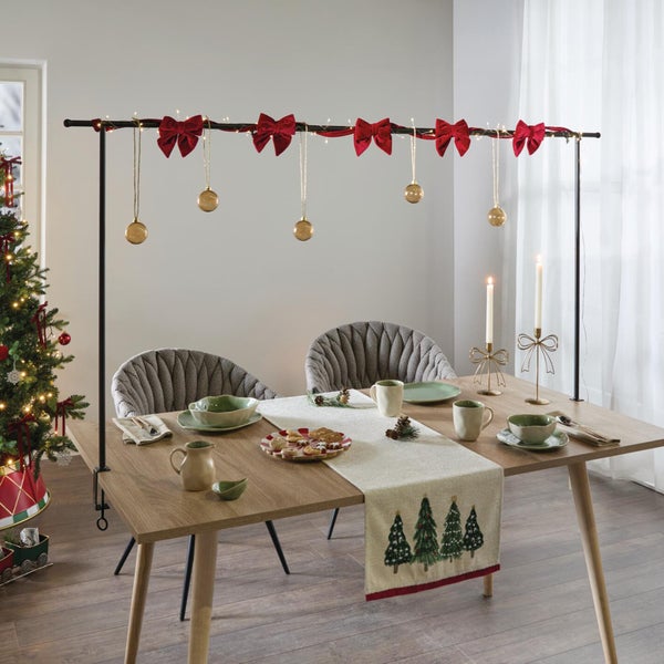 Dekorativer Tischaufsatz mit Klemmen für festliche Weihnachtsdekoration über einem Holztisch mit festlich gedecktem Geschirr.
