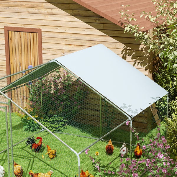 Großes Hühnergehege aus Metall mit Maschendraht und weißer Dachplane im Garten neben einem Holzschuppen.