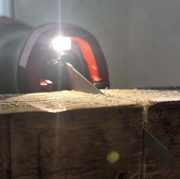 Akku-Säbelsäge mit integriertem Arbeitslicht beim Sägen eines Holzbalkens