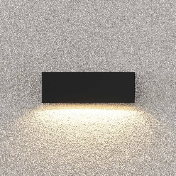 Rechteckige Wandleuchte für den Außenbereich mit nach unten gerichtetem Lichtstrahl auf einer strukturierten Wand.