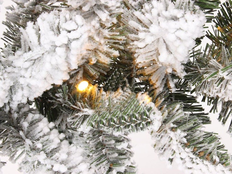 Detailansicht eines künstlichen Weihnachtsbaums mit künstlicher Schneebeschichtung und integrierter LED Lichterkette.