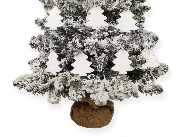 Künstlicher, beschneiter Weihnachtsbaum im Jutesack mit Tannenbaum Anhängern und Sternengirlande als Dekoration.